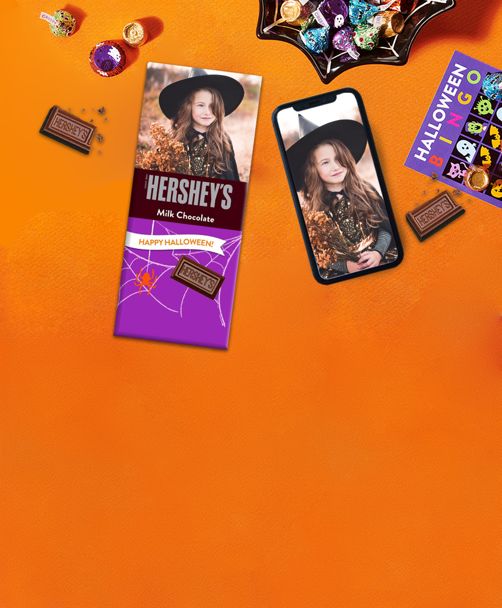 HERSHEY'S Bar with Halloween-themed personalized wrapper and iPhone on an orange background