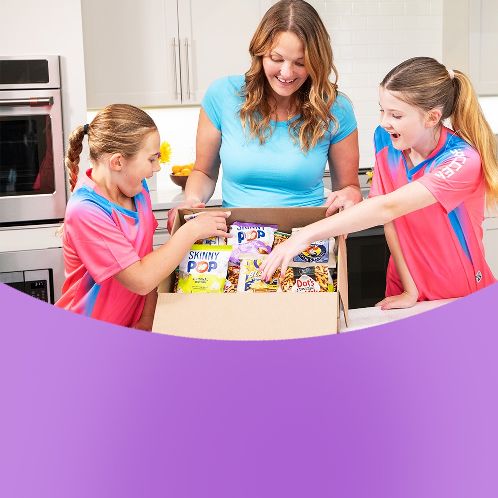 Promotional graphic featuring a family gathered around a kitchen island taking bags of snacks out of a multipack box