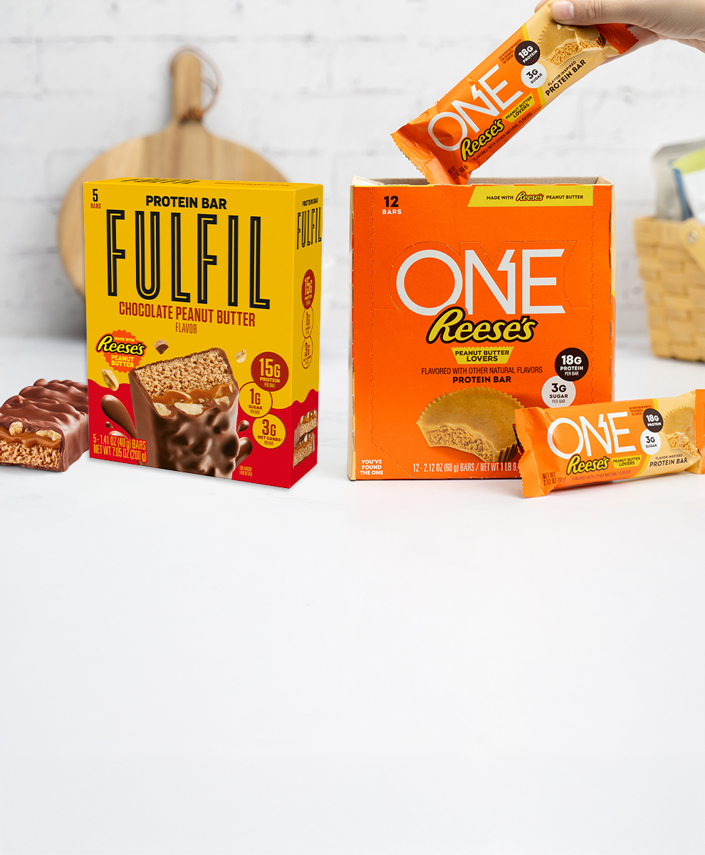 Promotional graphic featuring ONE and FULFIL Protein bar boxes displayed on a marble countertop