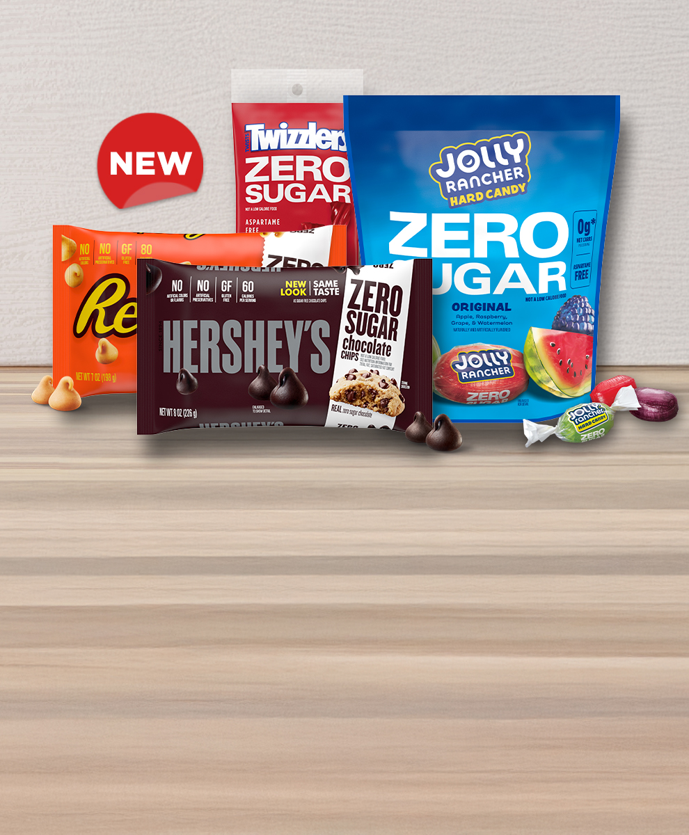 JOLLY RANCHER and TWIZZLERS zero sugar candy and HERSHEY'S and REESE'S zero sugar baking chips displayed on a wooden countertop