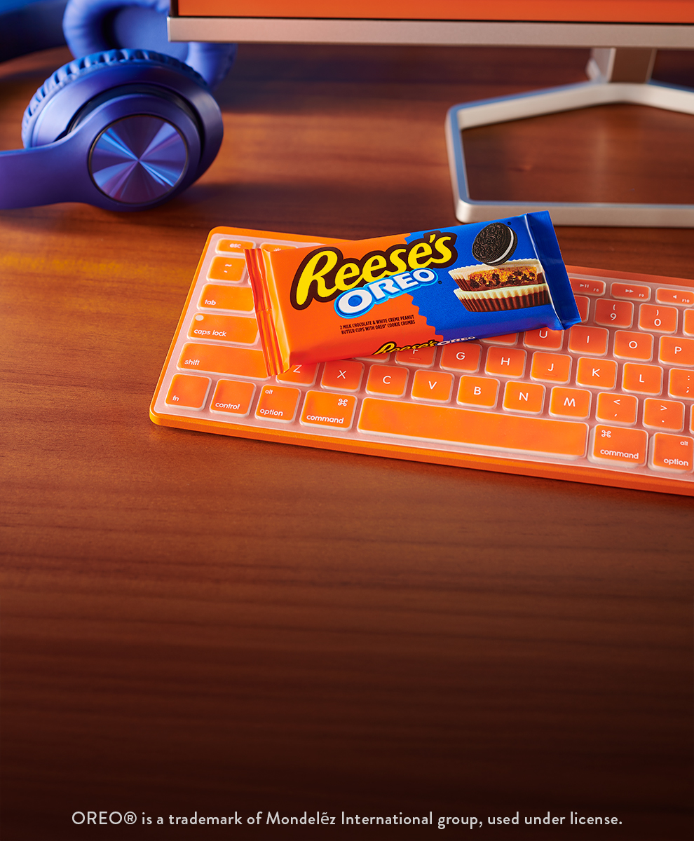 Promotional graphic featuring a pack of REESE'S OREO® Peanut Butter Cups sitting on a desk next to a keyboard and headphones