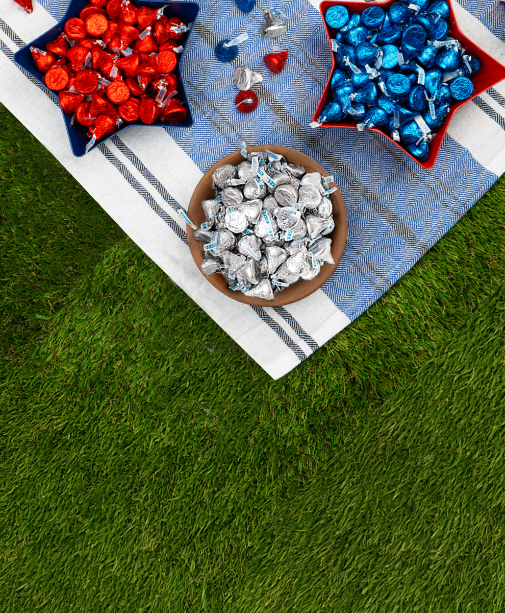 Promotional graphic featuring a picnic spread with Hershey's Kisses in Red and Silver and Blue Foils