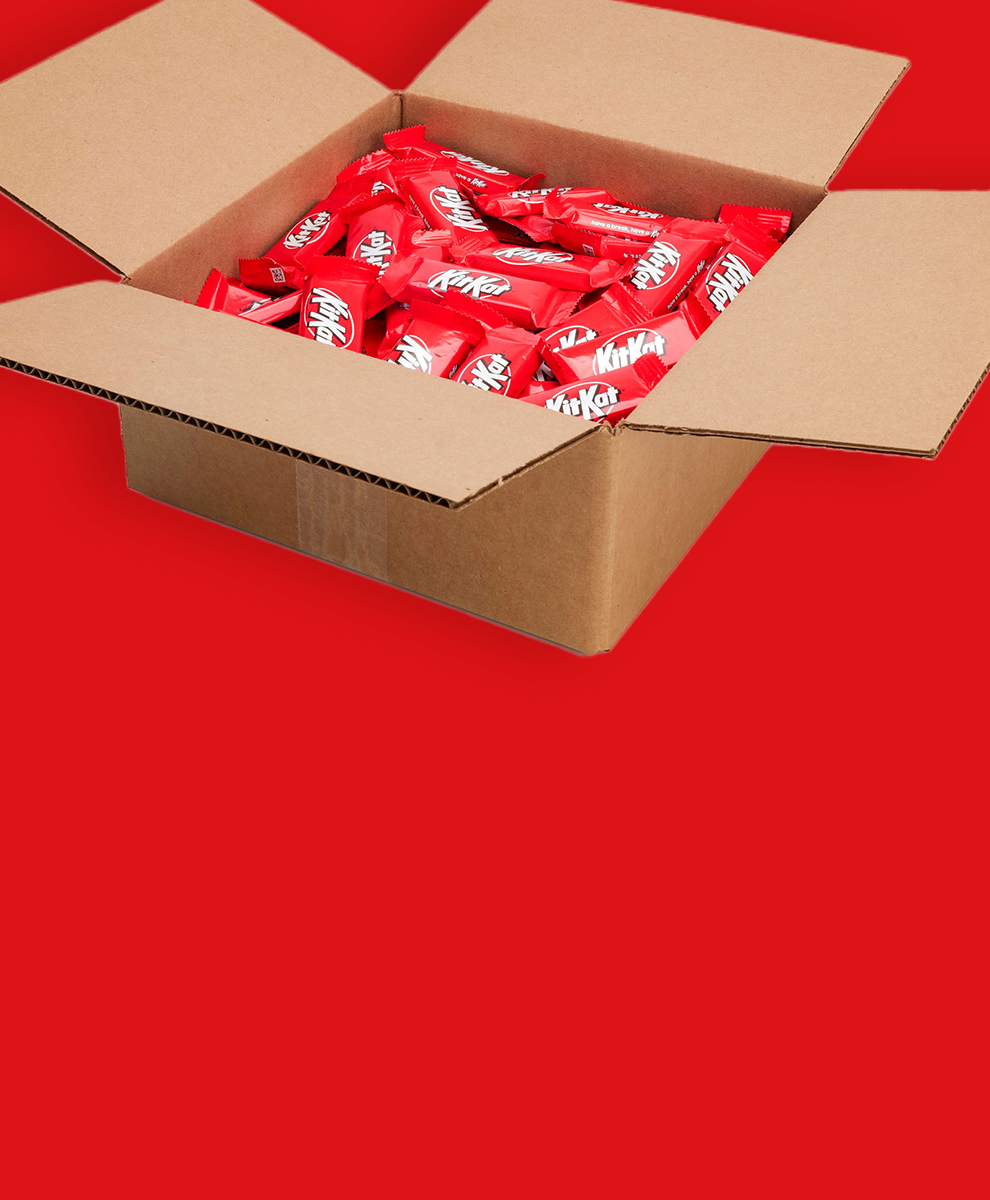 KIT KAT® snack size candies in a bulk cardboard box on a red background