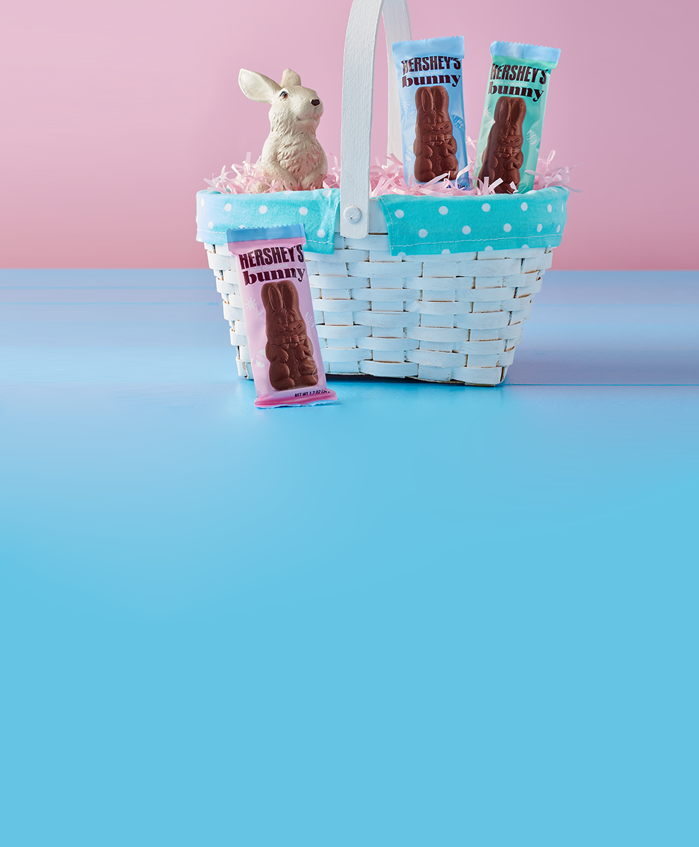 Wrapped HERSHEY'S Chocolate Bunnies nested in and around an Easter basket