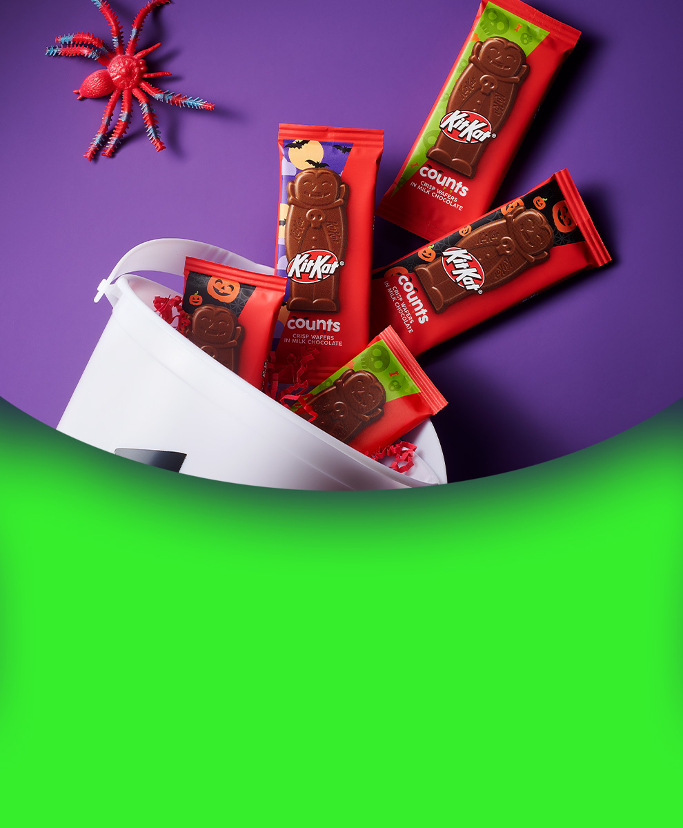 Promotional graphic featuring KIT KAT® Halloween Counts candy bars spilling out of a trick-or-treat bucket