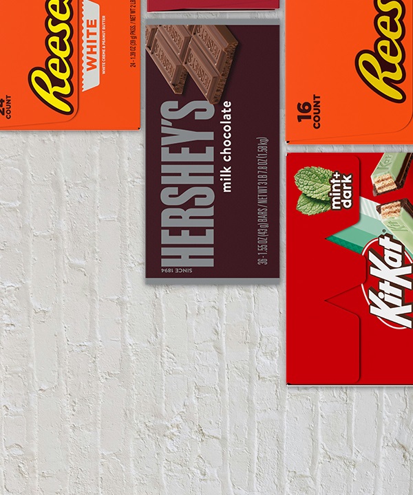 HERSHEY'S and REESE'S and TWIZZLERS and Kit Kat® and PAYDAY boxes of candy bars on a white brick background