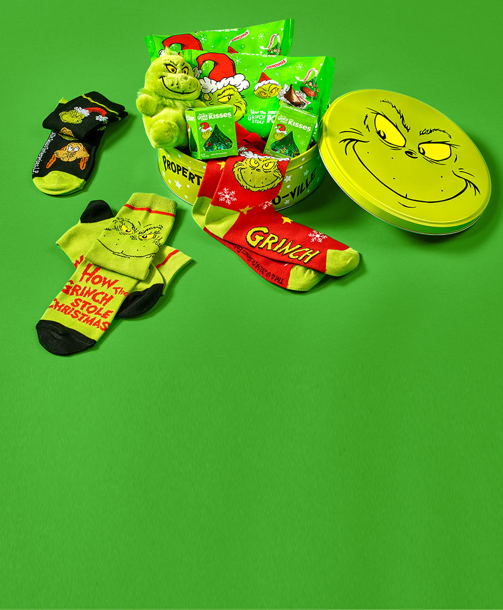 GRINCH gift tin open and unpacked on a solid green background