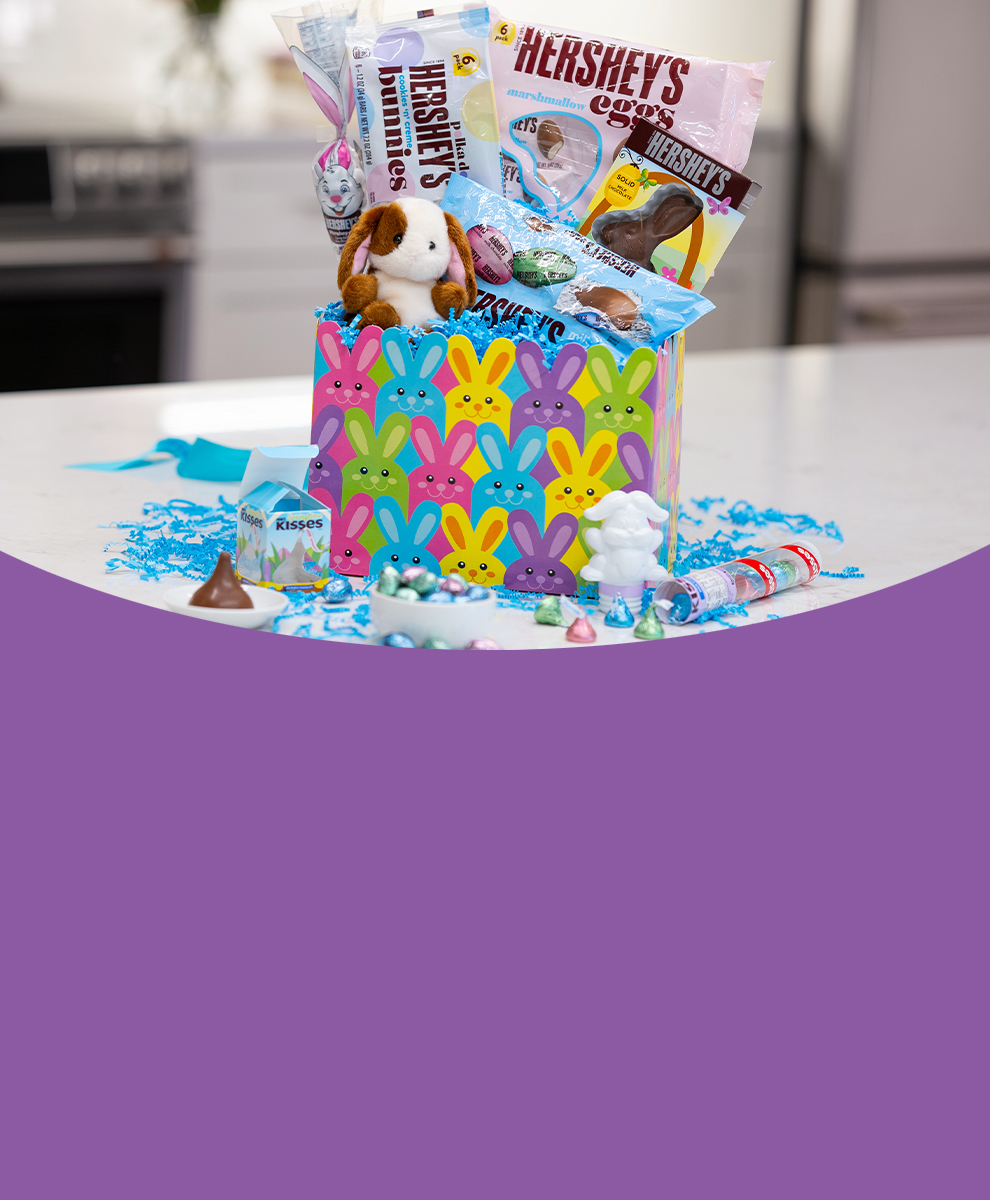 HERSHEY'S Easter basket filled with candy and a plush toy sitting on a marble countertop