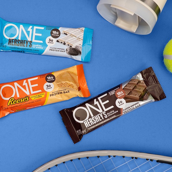 Promotional graphic featuring assorted flavors of ONE Brand protein bars on a blue background