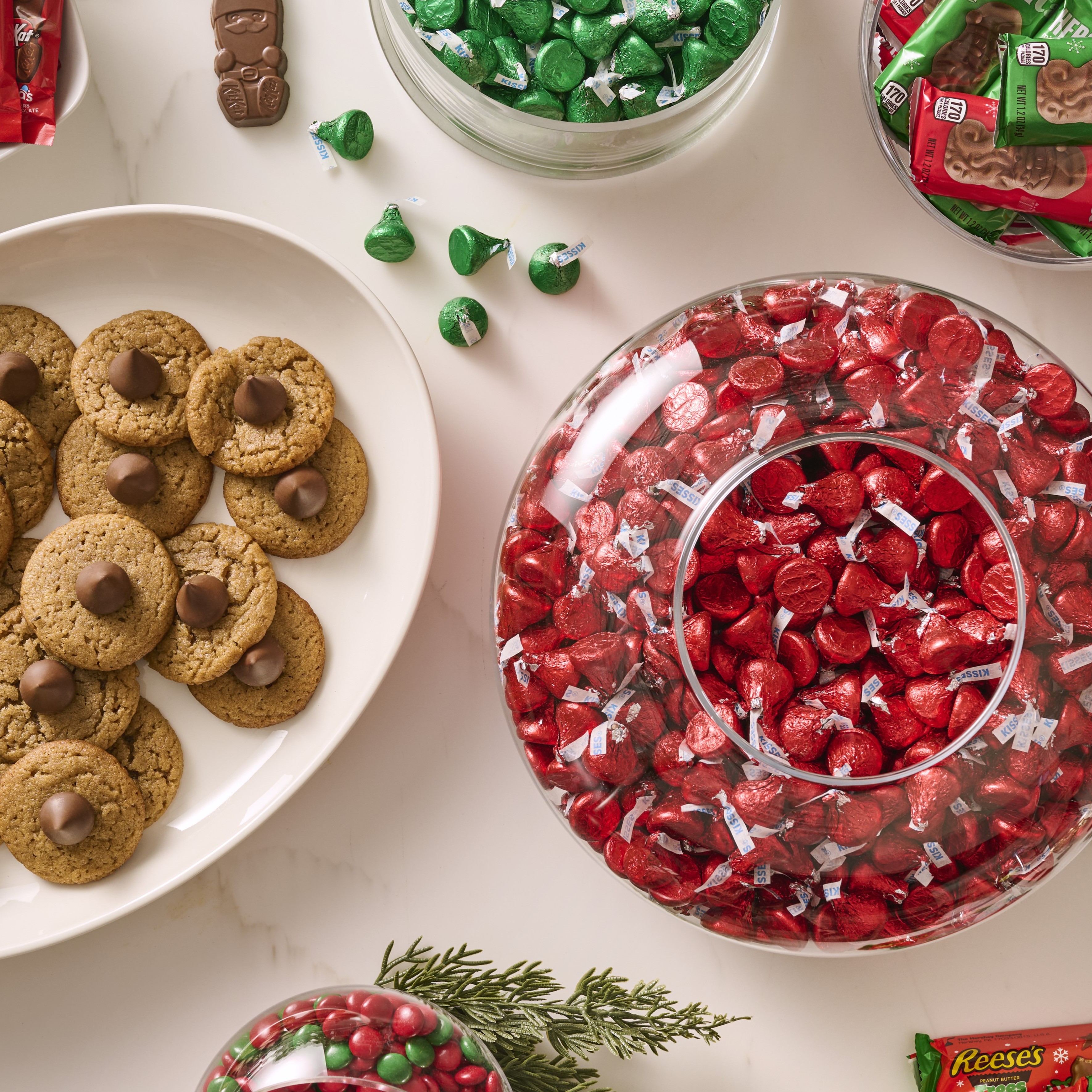 Promotional graphic featuring HERSHEY'S Kisses in red and green foils in assorted glass bowls