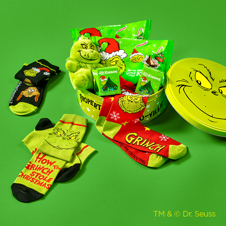 GRINCH holiday gift tin with top opened and contents laid out on a green background