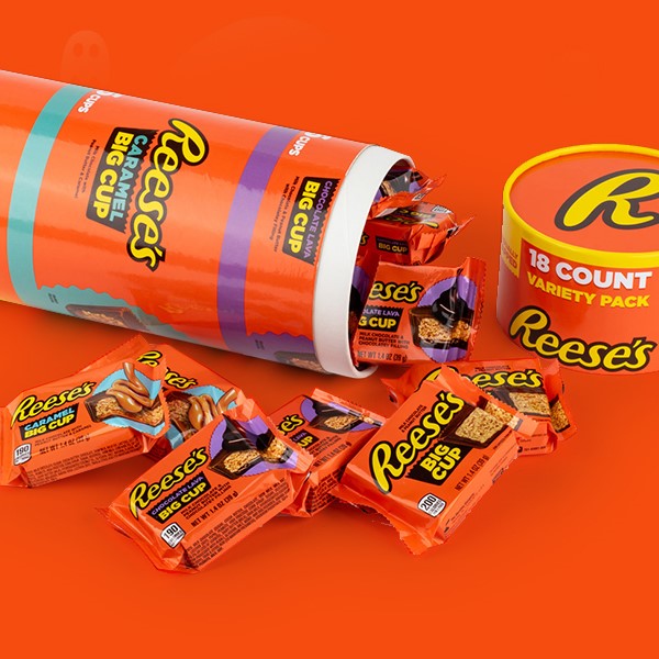 REESE'S Jumbo Sized Variety Pack tipped over and spilling out on an orange background