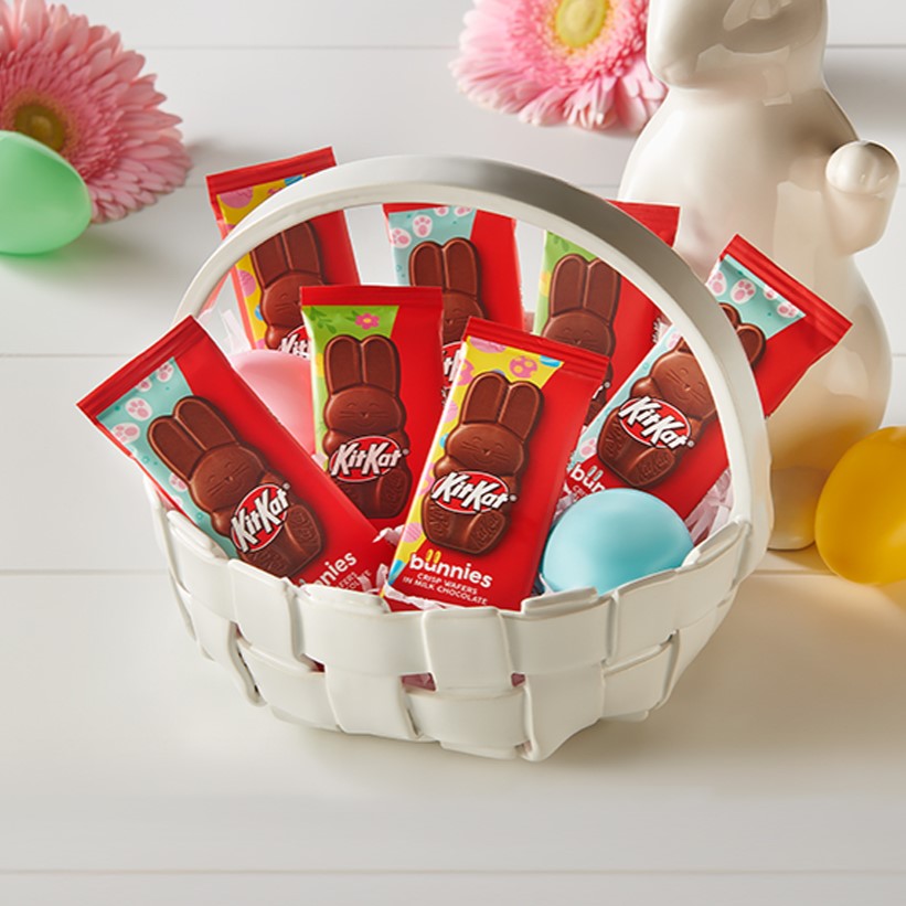 Promotional graphic featuring individually wrapped KIT KAT Milk Chocolate Bunnies in an Easter basket sitting on top of a table