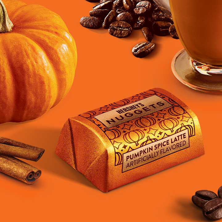 Promotional graphic featuring HERSHEY'S Pumpkin Spice Flavored Nuggets Candy in a fall-themed setting