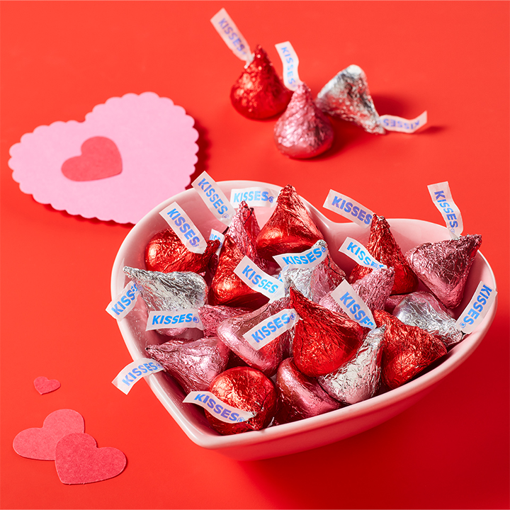 HERSHEY'S Kisses in red and pink and silver foils in a heart shaped bowl