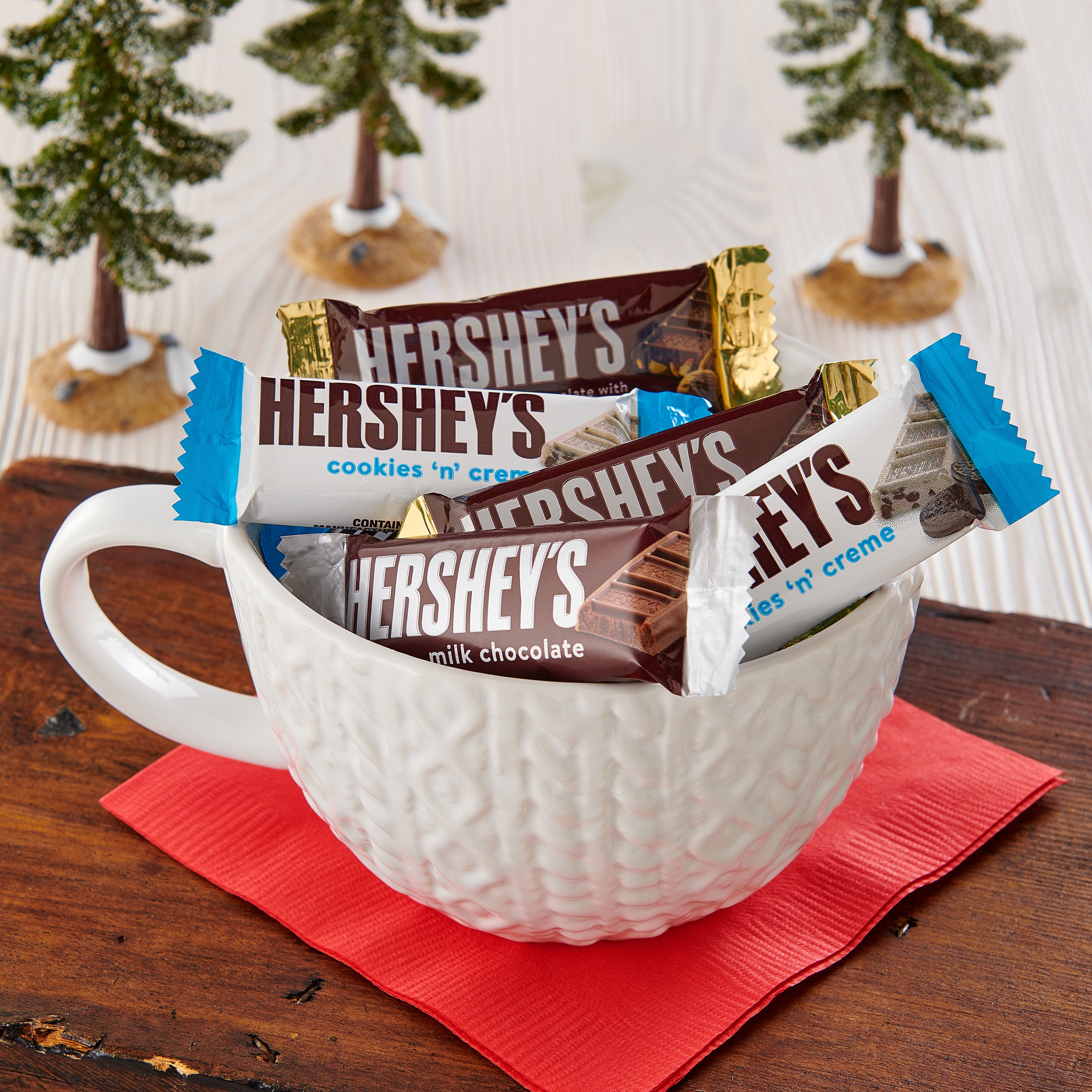 HERSHEY'S assorted snack size bars in a mug surrounded by winter-themed decor