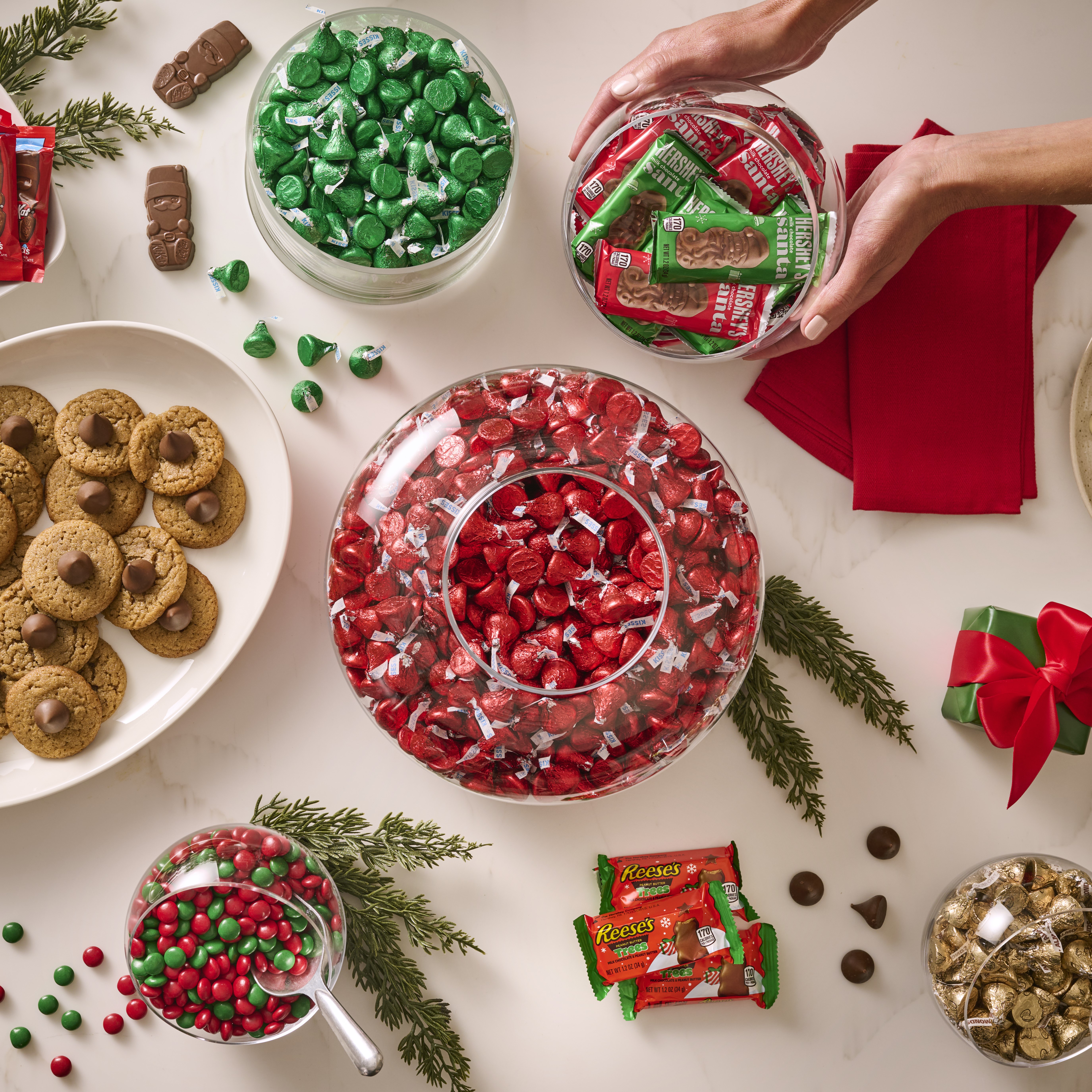 Holiday-themed table spread with assorted bowls and plates of HERSHEY'S and REESE'S candies