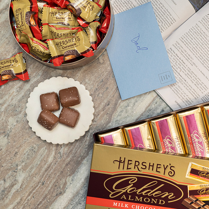 Promotional graphic with a Father's Day gifting theme featuring a HERSHEY'S GOLDEN ALMOND milk chocolate candy bars and WORLD'S LARGEST Reese's cups