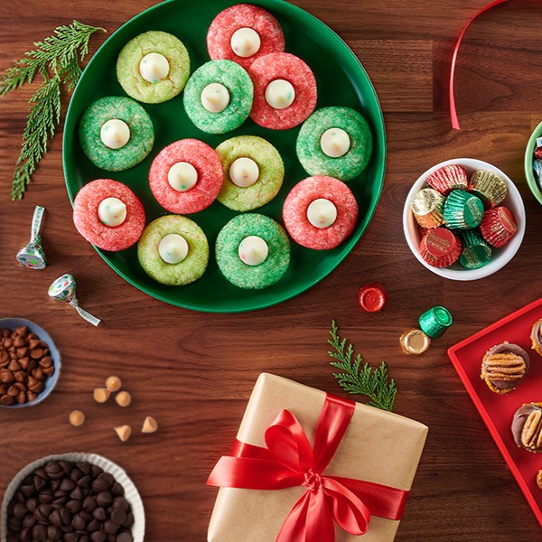 Holiday-themed baking spread with assorted bowls of HERSHEY'S baking chips and REESE'S miniature peanut butter cups