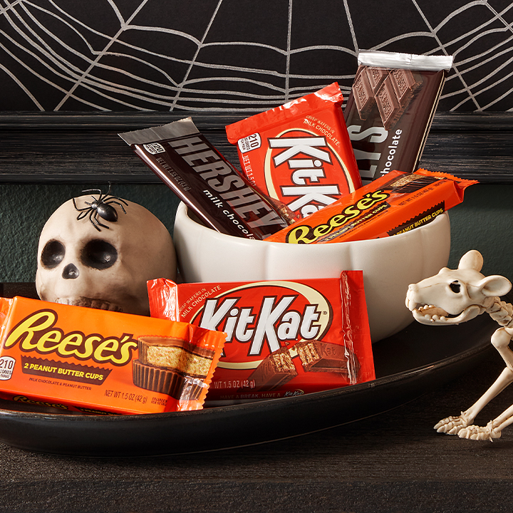 Promotional graphic featuring assorted full size candy bars in a Halloween-themed bowl