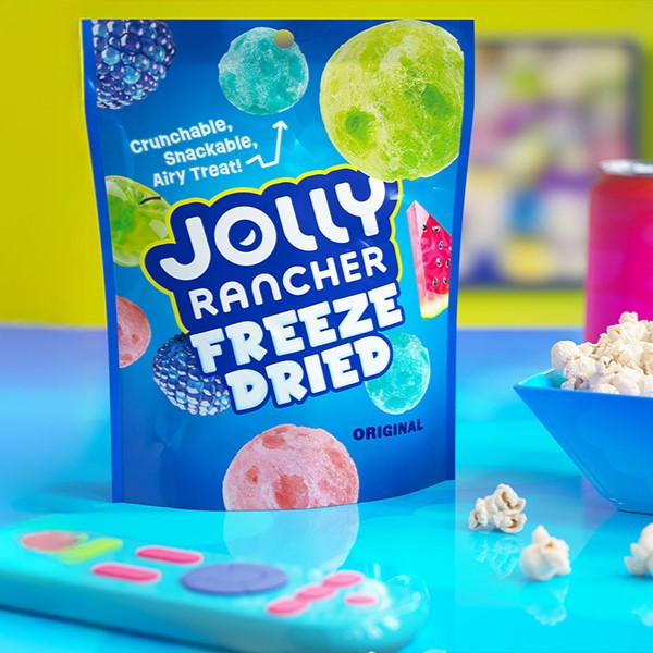 Promotional graphic featuring JOLLY RANCHER Freeze-Dried Candy stand-up pouch sitting on a table