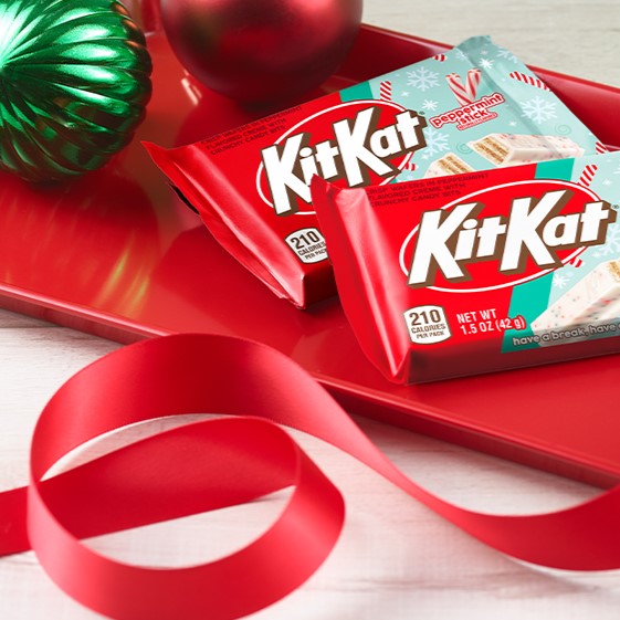 Promotional graphic featuring standard size packs of KIT KAT® Peppermint Stick candy on a red platter