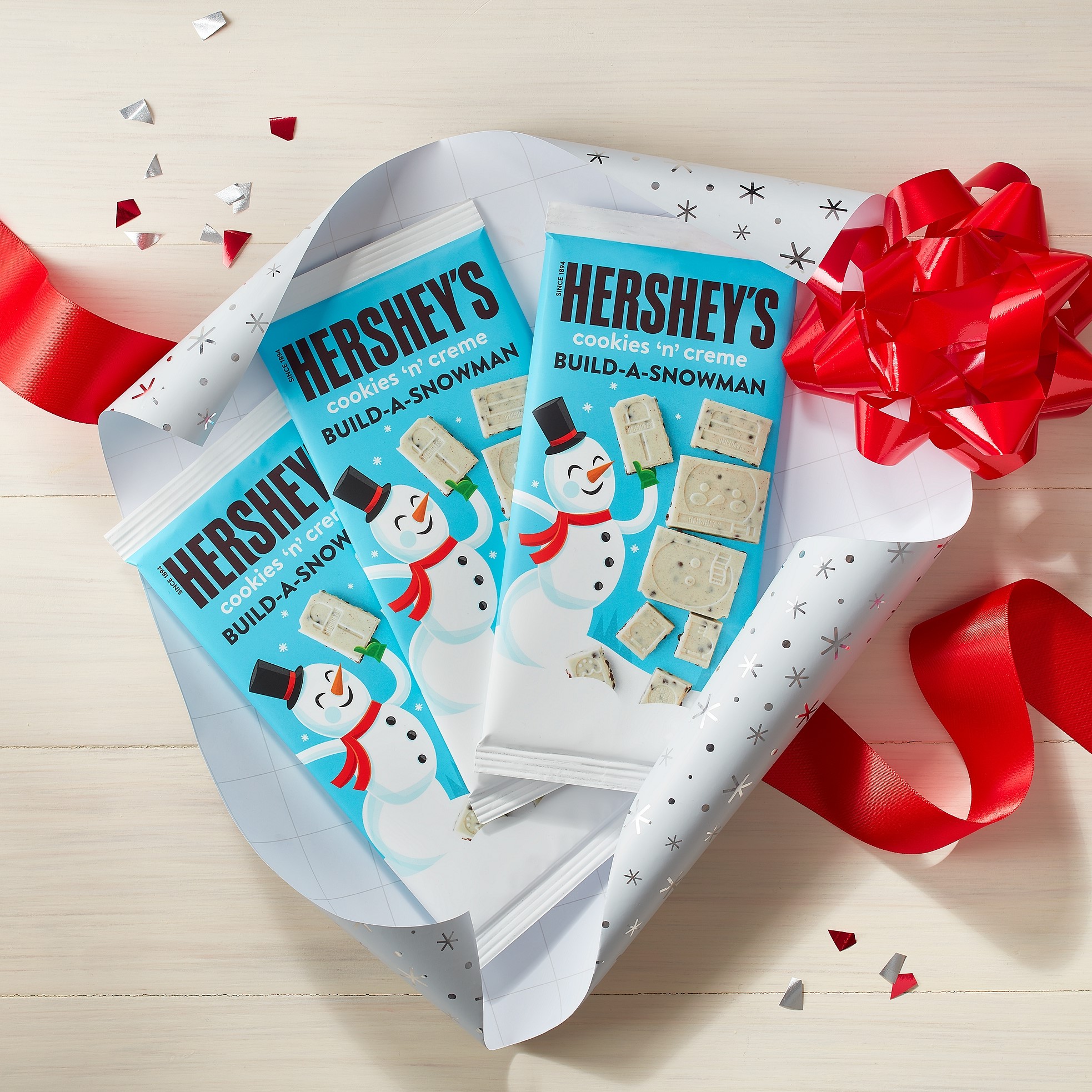HERSHEY'S Build-A-Snowman XL Bars partially unwrapped alongside holiday-themed ribbon