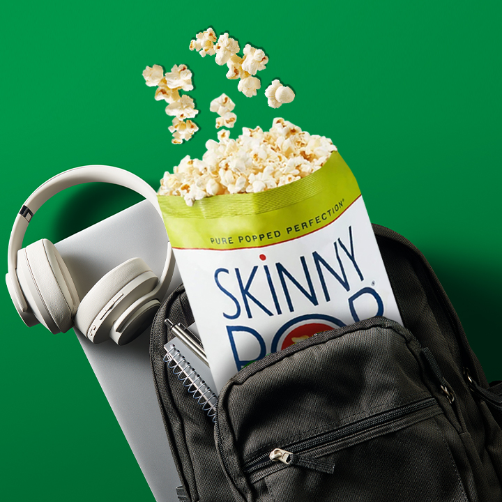 Bag of SKINNYPOP inside a backpack with headphones and a laptop