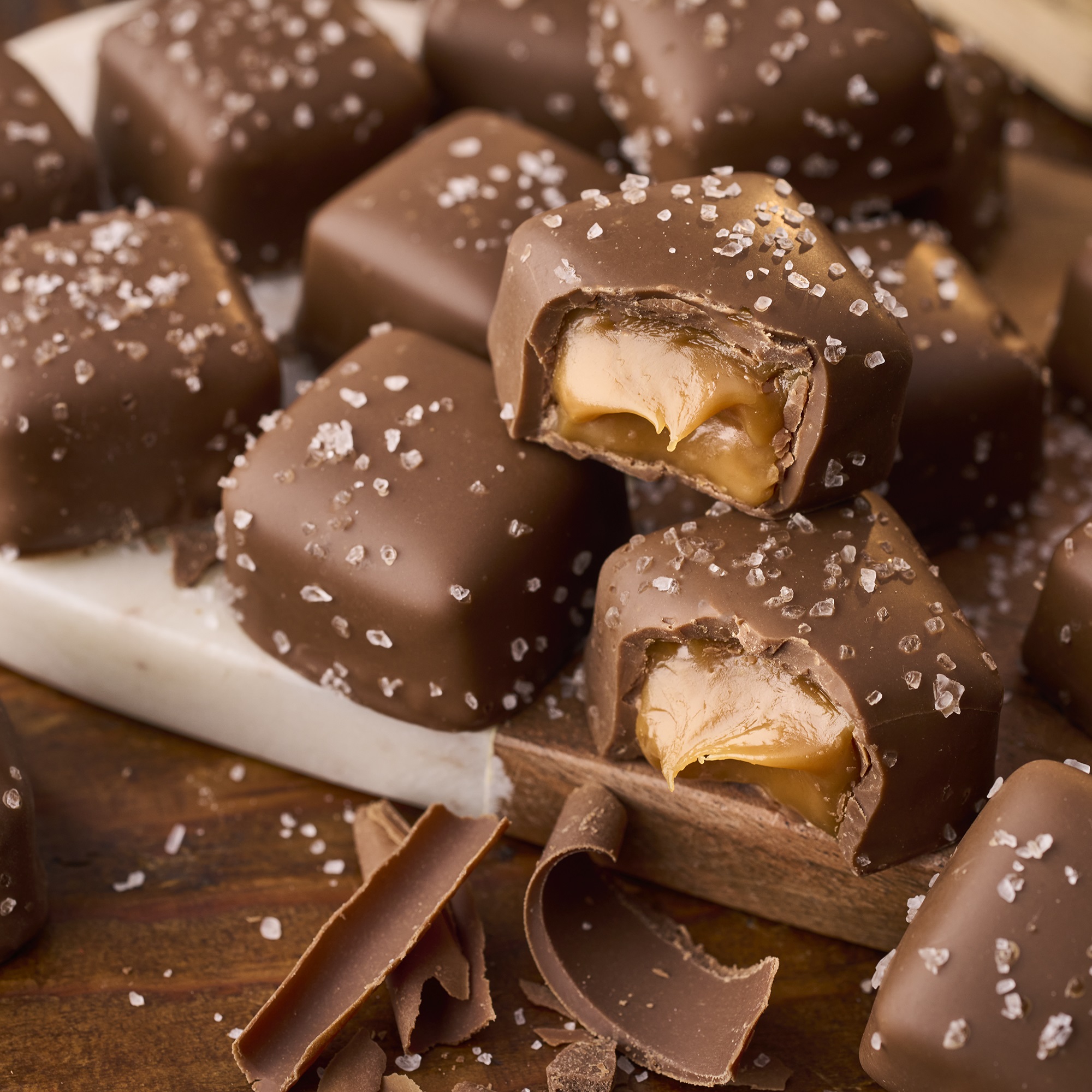 HERSHEY'S Caramels stacked on a serving board atop a wooden table