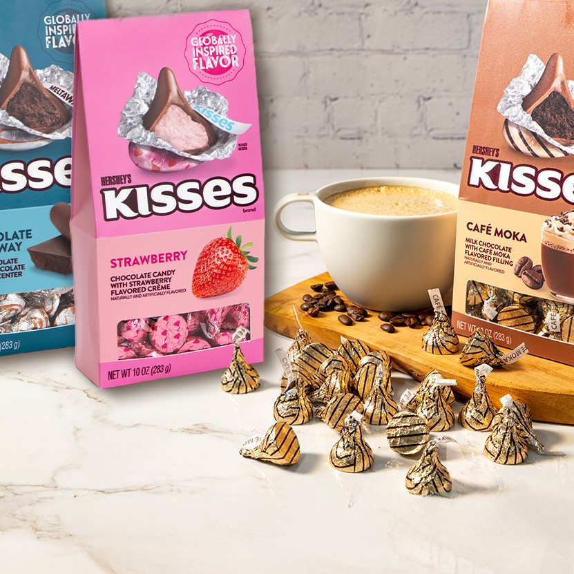 Promotional graphic showing HERSHEY'S Flavors of the World Kisses on a marble countertop next to a cup of coffee